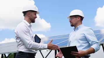 dos masculino ingeniero vistiendo la seguridad chaleco apretón de manos con solar paneles antecedentes. negocio proyecto acuerdo y acuerdo en industrial de renovable y verde energía concepto video