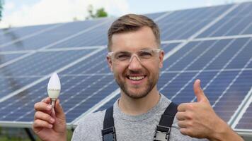 ingeniero en pie con lámpara en solar panel y sensación libertad a ver punto. electricista trabajando en comprobación y mantenimiento equipo a industria solar poder video