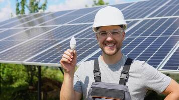 ingegnere in piedi con lampada su solare pannello e sensazione la libertà a Visualizza punto. elettricista Lavorando su controllo e Manutenzione attrezzatura a industria solare energia video