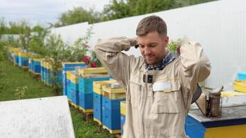 Imker setzt auf schützend Anzug. jung Imker setzt auf schützend passen zum Schutz Vor Arbeiten beim Biene Haus Bienenhaus mit Bienen fliegend video