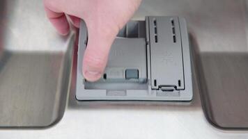 A man's hand puts a dishwasher pill in a close-up dishwasher in the kitchen video