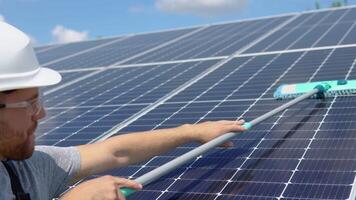 Worker cleans solar panel with water clean at solar power plant video