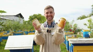 porträtt av biodlare med en två burkar med färsk honung. biodling begrepp. biodlare skörd honung video