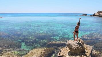 Beautiful caucasian woman stand on viewpoint rock enjoy crystal clear waters and mediterranean seascape panorama on summer holiday vacation. Happiness and travel explore concept video