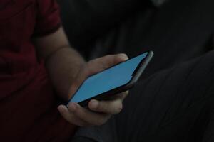 Hand holding smartphone in office, using phone photo