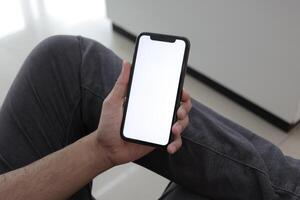 Hand holding smartphone in office, using phone photo