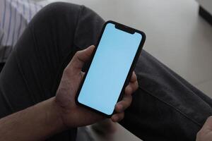 Hand holding smartphone in office, using phone photo