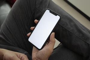 Hand holding smartphone in office, using phone photo