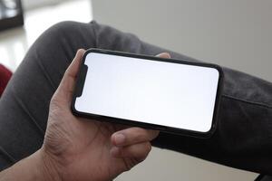 Hand holding smartphone in office, using phone photo