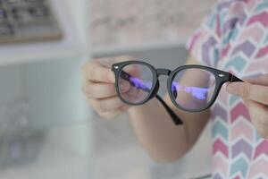 Hand holding glasses in optical store, eyeglasses in hand photo