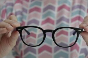 Hand holding glasses in optical store, eyeglasses in hand photo