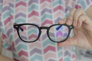 Hand holding glasses in optical store, eyeglasses in hand photo