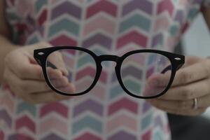 Hand holding glasses in optical store, eyeglasses in hand photo