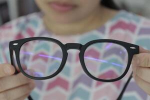 Hand holding glasses in optical store, eyeglasses in hand photo