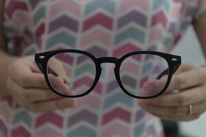 Hand holding glasses in optical store, eyeglasses in hand photo