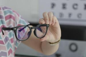 Hand holding glasses in optical store, eyeglasses in hand photo