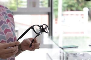 Hand holding glasses in optical store, eyeglasses in hand photo