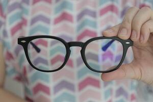 Hand holding glasses in optical store, eyeglasses in hand photo