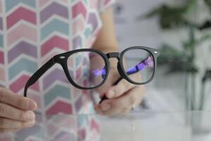 Hand holding glasses in optical store, eyeglasses in hand photo