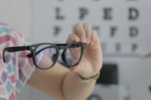 Hand holding glasses in optical store, eyeglasses in hand photo