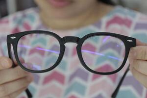 Hand holding glasses in optical store, eyeglasses in hand photo