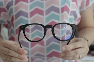 Hand holding glasses in optical store, eyeglasses in hand photo