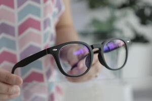 Hand holding glasses in optical store, eyeglasses in hand photo