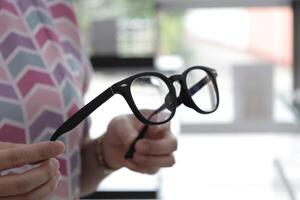 Hand holding glasses in optical store, eyeglasses in hand photo