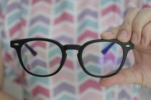 Hand holding glasses in optical store, eyeglasses in hand photo