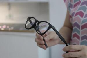 Hand holding glasses in optical store, eyeglasses in hand photo