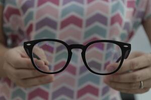 Hand holding glasses in optical store, eyeglasses in hand photo