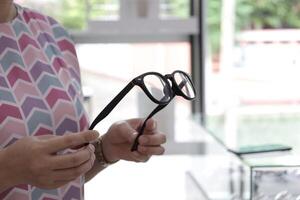 Hand holding glasses in optical store, eyeglasses in hand photo