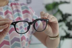 Hand holding glasses in optical store, eyeglasses in hand photo