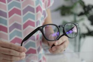 Hand holding glasses in optical store, eyeglasses in hand photo