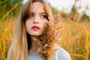 Beautiful young girl wearing blank gray t-shirt and black jeans posing against high green and yellow grass in early warm autumn. Outdoor portrait of beautiful female model. photo