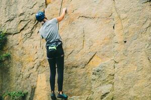 Young athletic woman in equipment doing rock climbing outdoors. Training area for outdoor activities. Extreme sport. photo