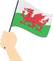 Hand holding and raising the national flag of Wales vector