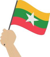 Hand holding and raising the national flag of Myanmar vector