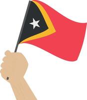 Hand holding and raising the national flag of Timor Leste vector