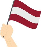 Hand holding and raising the national flag of Latvia vector