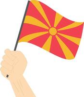 Hand holding and raising the national flag of Macedonia vector