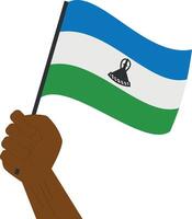 Hand holding and raising the national flag of Lesotho vector