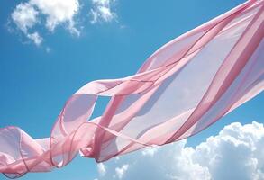 Flying pink transparent fabric wave on blue sky background and illuminated by sunlight photo