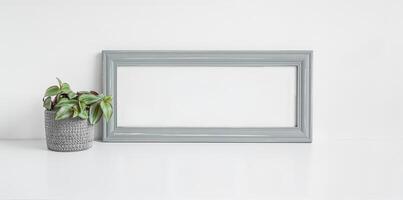 Gray mock up photo frame and home plant Tradescantia zebrina