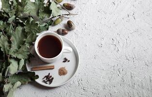 Cup of acorn coffee, acorns and autumn oak leaves on a gray background photo