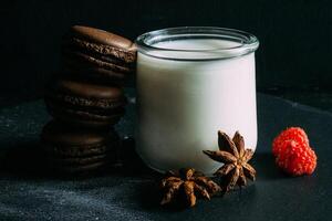 a glass jar with chocolate and macaroons on a black background photo