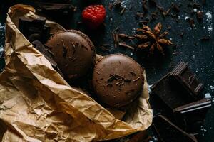 chocolate macarons con frambuesa y chocolate en un oscuro antecedentes foto