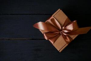 a brown gift box with a brown ribbon on a black table photo