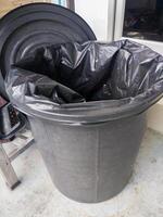 A black garbage bag in a black plastic trash can. photo