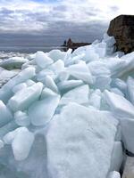 Crystalline ice sheets fracture and float on Russia's Lake Ladoga, capturing the stark beauty of spring's thaw under a clouded sky. photo